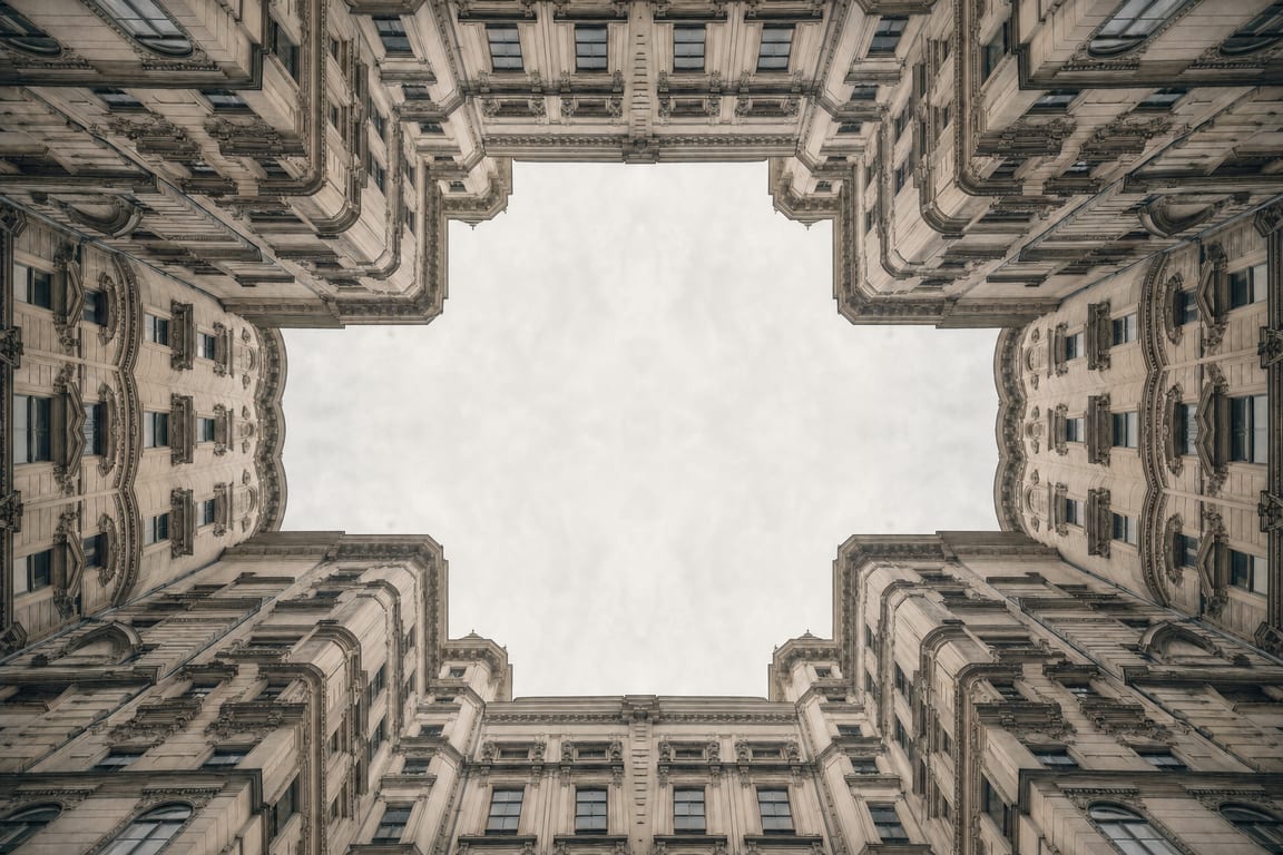 Innenhof aus der Untersicht, warm getont. Die Gesimse rahmen ein sechseckiges Stück hellen Himmel.
